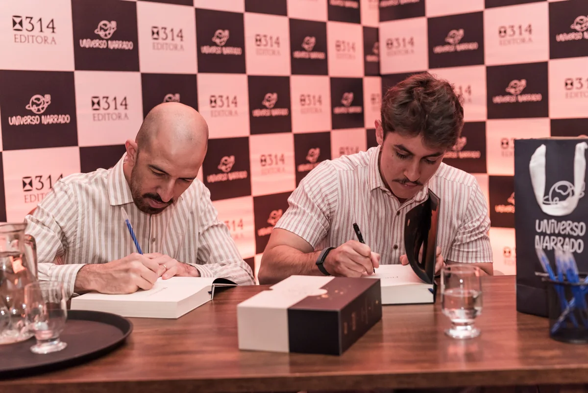Os dois autores autografando exemplares lado a lado