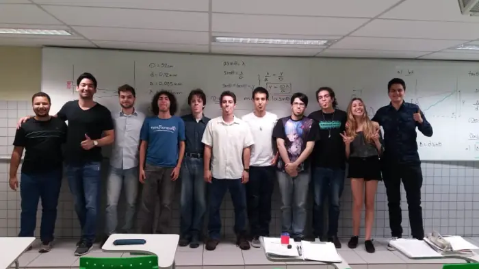 Felipe com uma turma de alunos em frente ao quadro branco cheio de fórmulas
