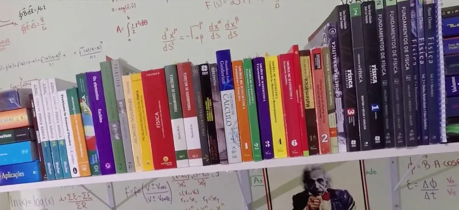 Estante de livros de física e matemática numa parede cheia de fórmulas