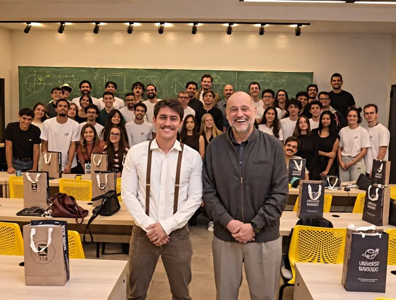 Felipe com um professor e uma turma de alunos num evento do Universo Narrado